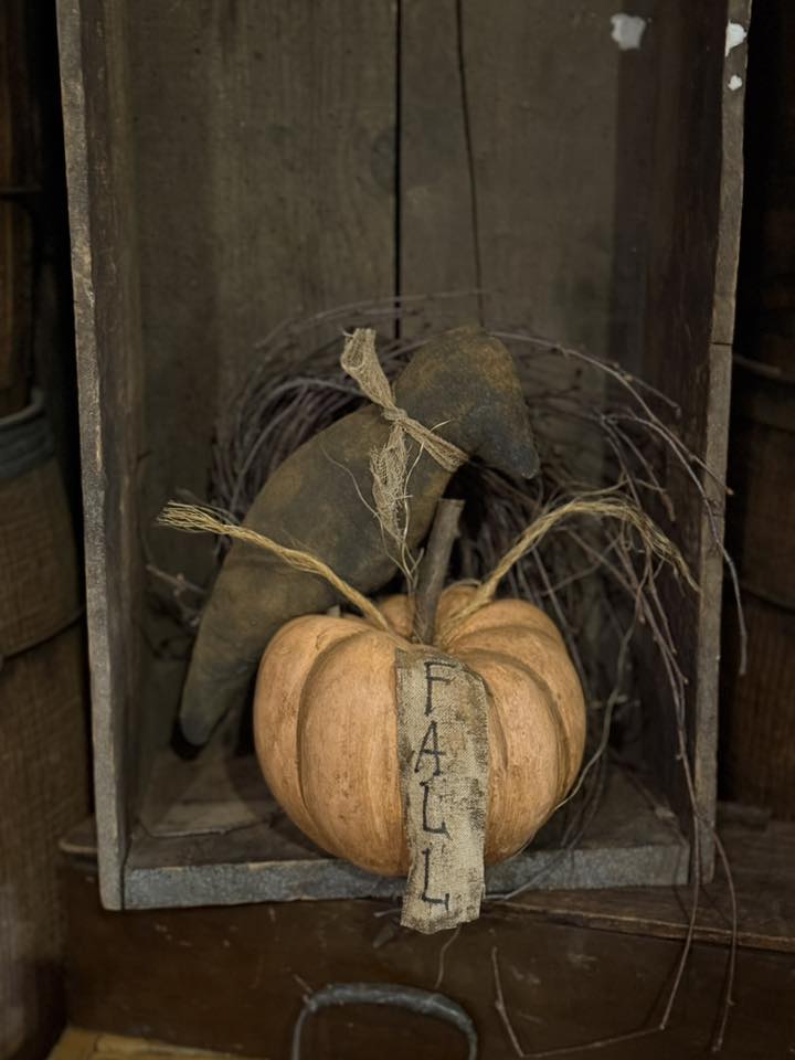 Decorative pumpkin with a 'Fall' sign in a rustic wooden box.