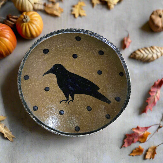 Round stoneware plate with a black silhouette of a bird on a beige background