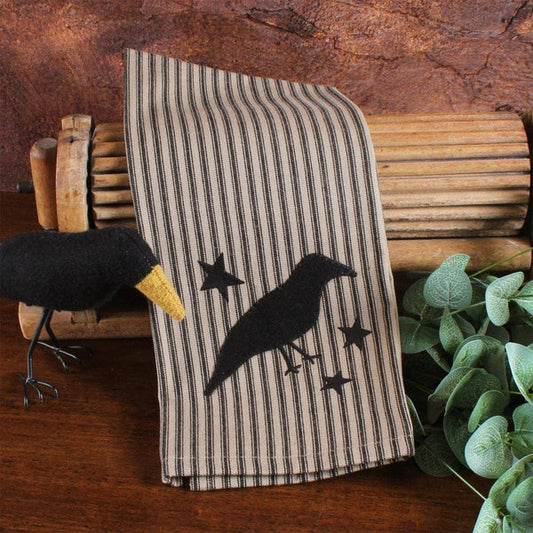 Striped towel with crow and star design on a wooden surface with decorative items.