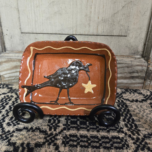 Small rectangular redware plate with a crow and a star hanging from its beak