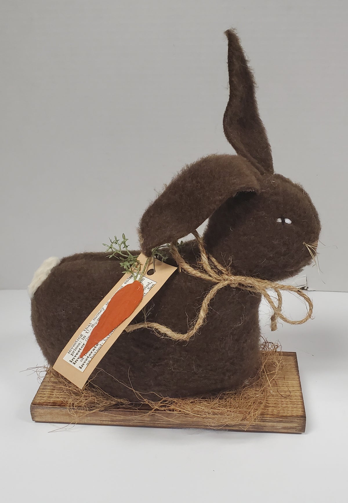 Brown felt bunny with carrot tag on a white background