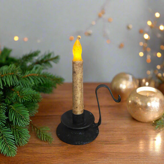 Decorative candle with cork base and black holder on a wooden surface with festive decorations.
