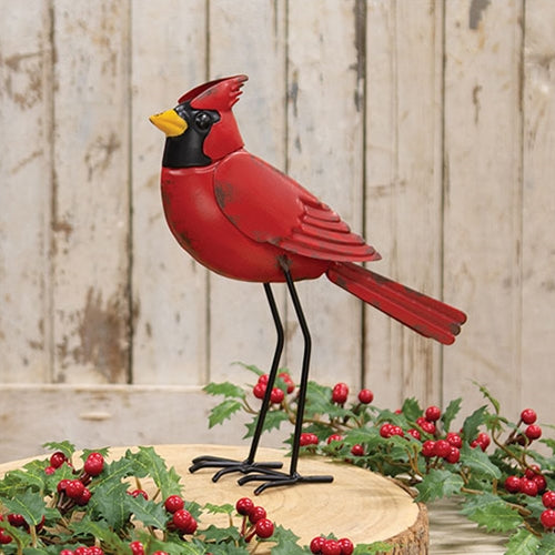 Red cardinal bird figurine on a wooden base with holly berries against a wooden background