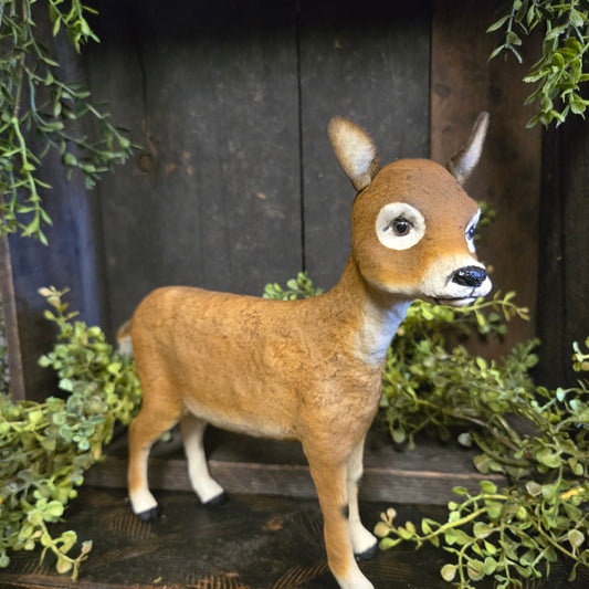 Stuffed deer toy with greenery in a rustic setting