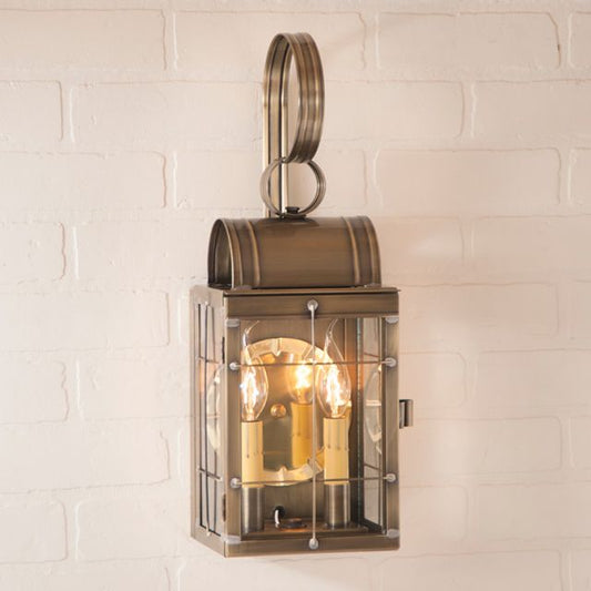 Bronze outdoor wall light fixture on a white brick wall