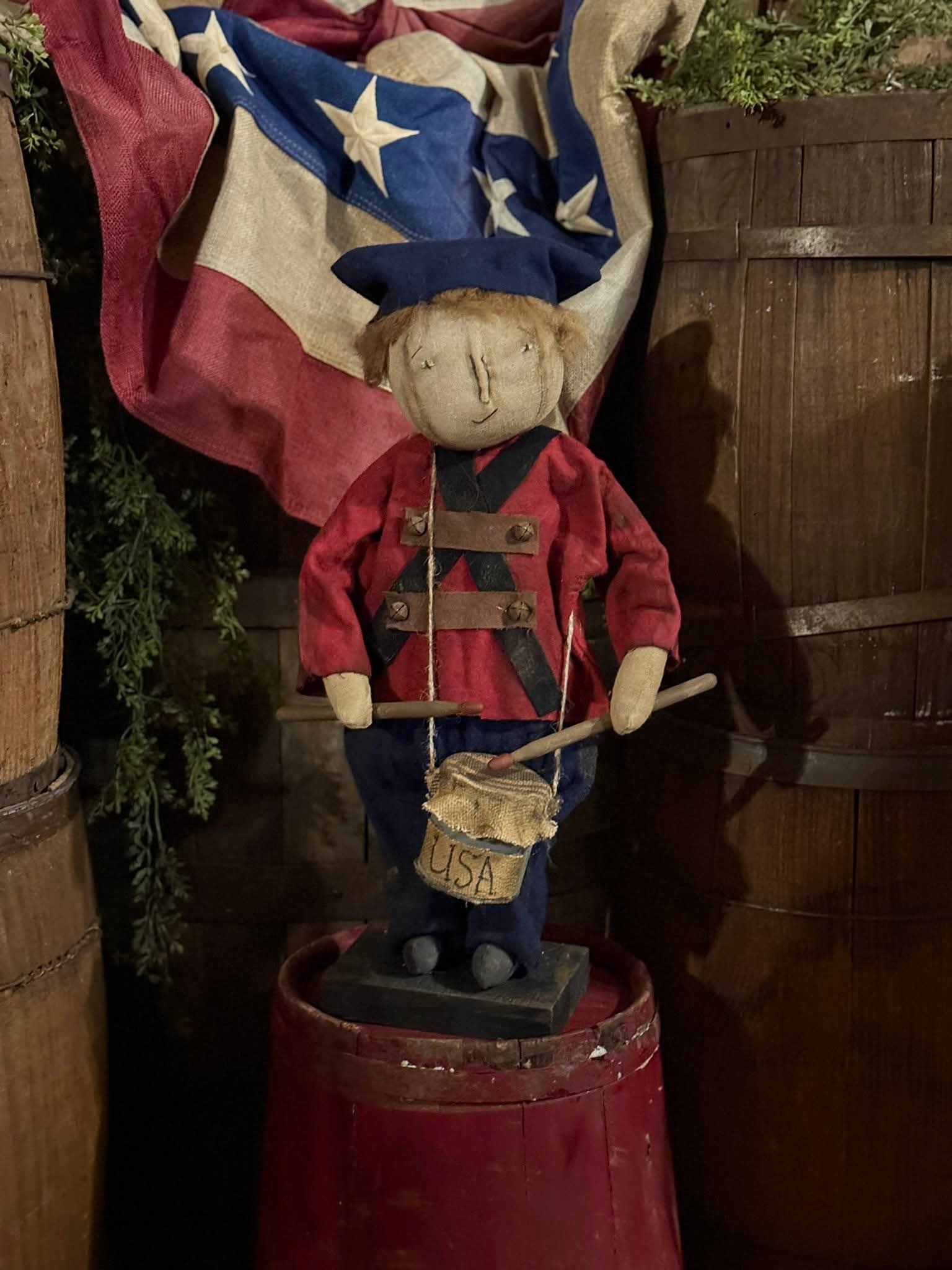 Vintage-style figurine of a drummer boy with a flag, standing on a red barrel.