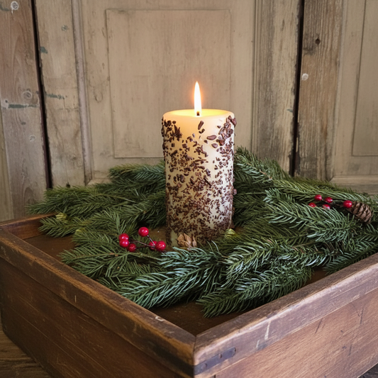 Decorative candle with greenery in a wooden box against a rustic wooden background