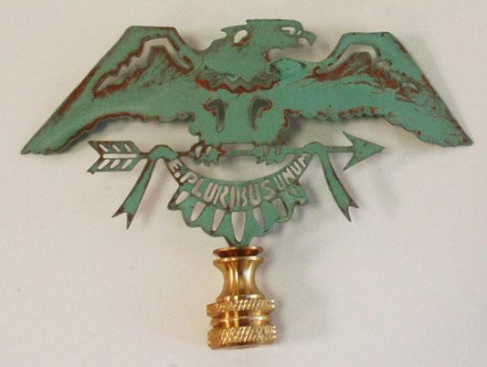 A copper verdigris lamp finial designed as an eagle with outstretched wings, with a gold-tone embellishment at the bottom.