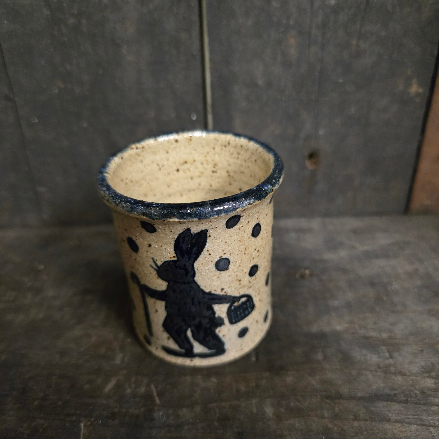 Ceramic cup with black speckles and a black design on a dark surface