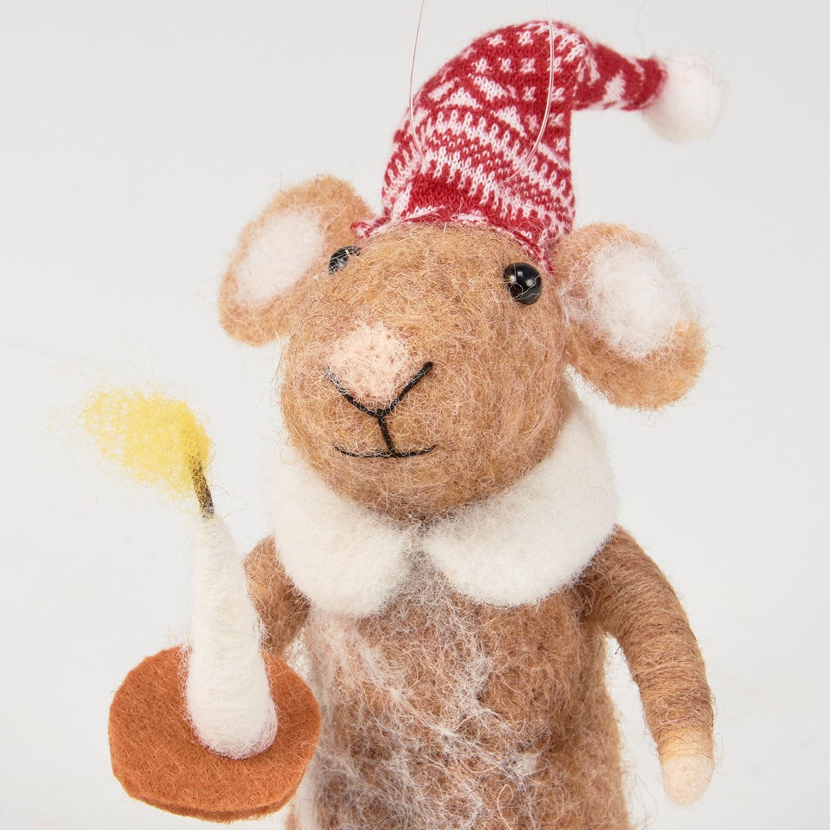 Close up of felted mouse in red hat holding a candle on a white background.
