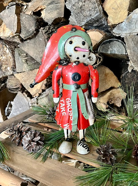 Metal snow woman with red outfit and hat with rocks in background