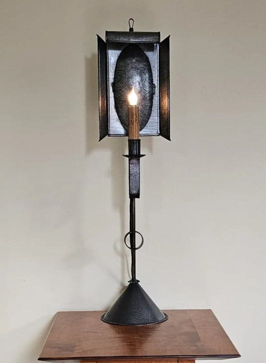 Decorative black lantern with a candle on a wooden surface against a plain wall.
