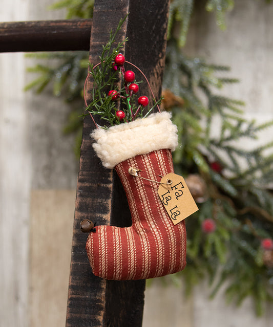 Small red and white striped Christmas stocking with a 'Fa La La' tag, hanging on a rustic wooden background.