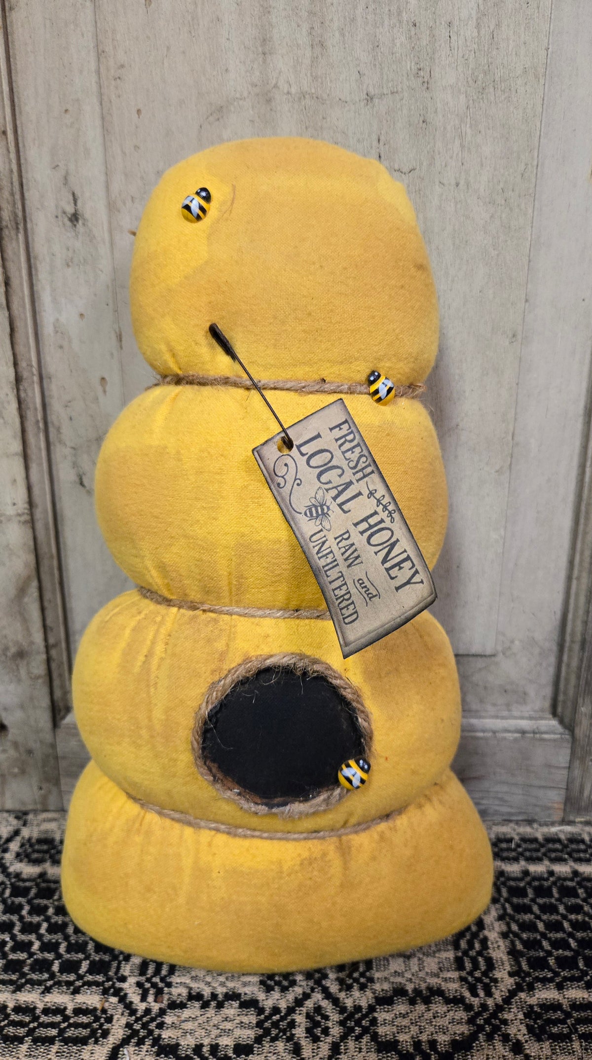 Yellow bee house with a tag labeled 'Local Honey' against a wooden background