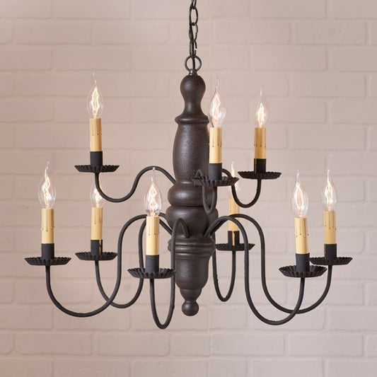 Dark bronze chandelier with candle-style lights against a light brick wall.