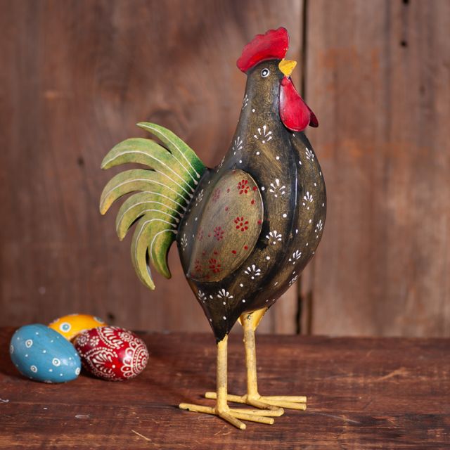 Decorative rooster figurine with colorful eggs on a wooden surface