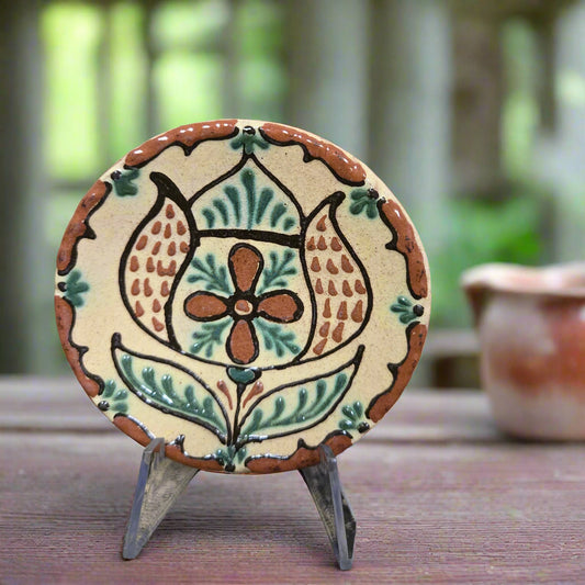 Small round redware plate with a fancy tulip and an intricate border design