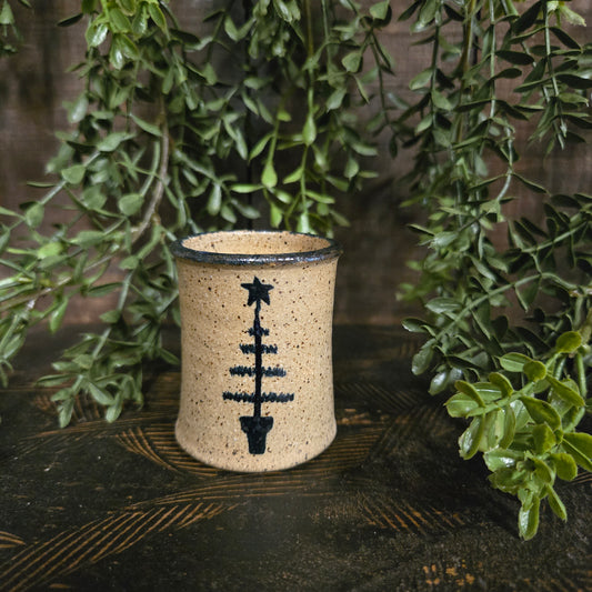 Mini stoneware crock with feather tree motif on a textured wood surface with greenery