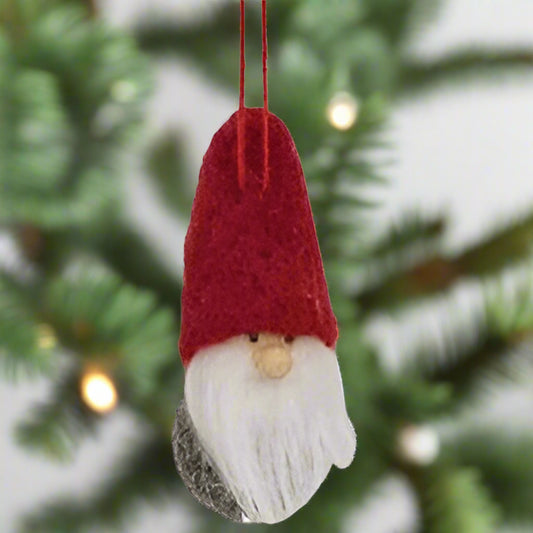 A felted mini red hat gnome ornament with a face, white beard, and red hat, with a red string hanger.