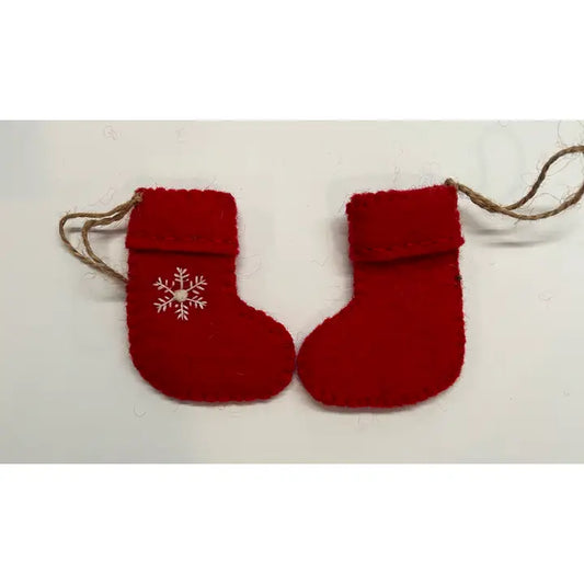Two red felted wool ornaments shaped like stockings with a white embroidered snowflake on the front and a visible hanging loop.
