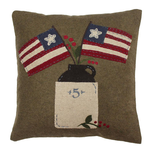 A square-shaped wool felt pillow with a design that includes two American flags, a rustic jug, and berries on a khaki background.