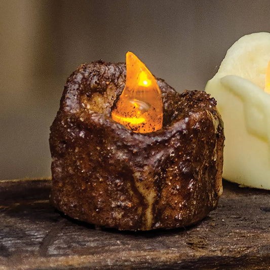 Decorative candle with a glowing orange tip on a rustic surface