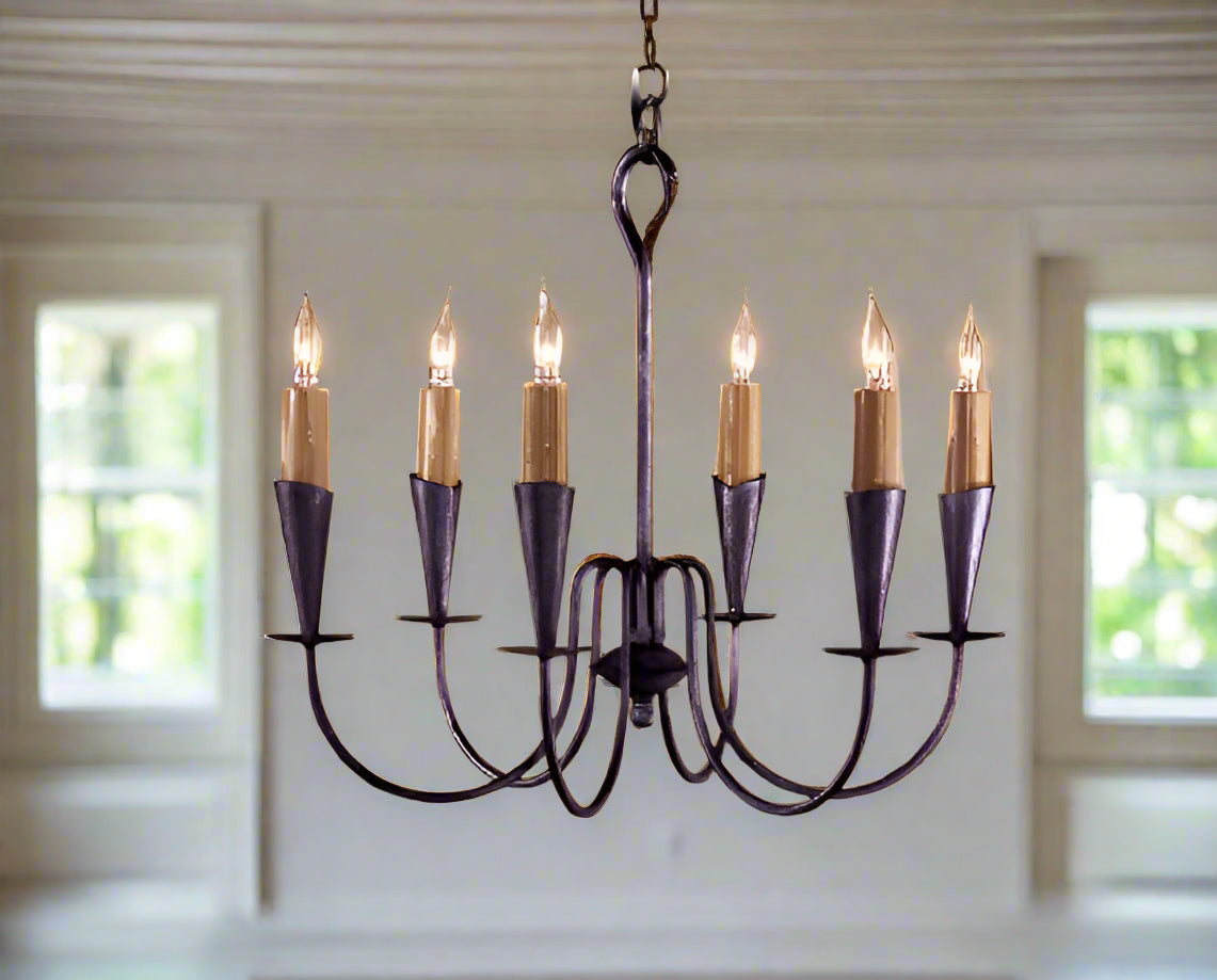 A wrought iron chandelier with six lights, featuring a dark color and a classic design.