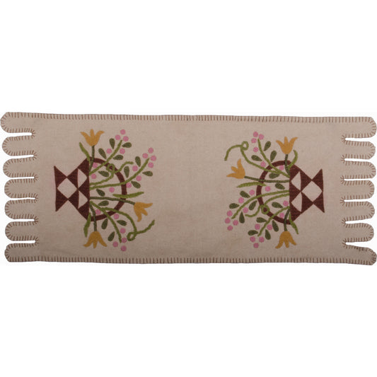 A cream-colored table runner with a floral basket design in the center, featuring embroidered details.