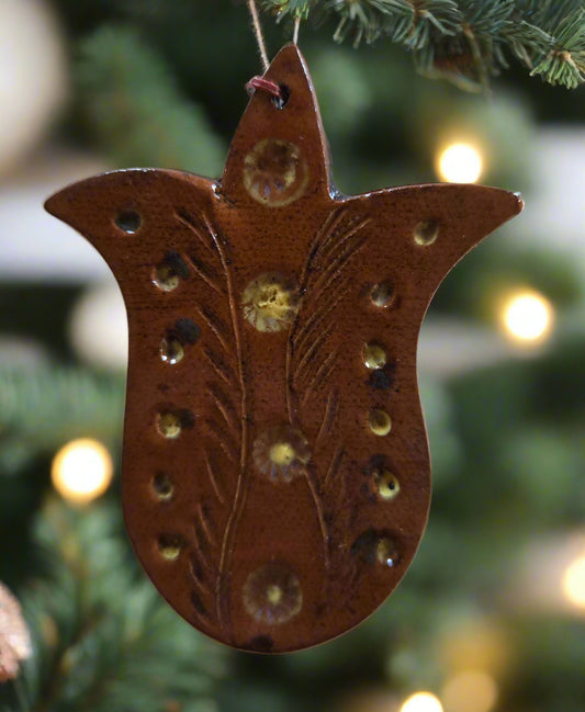 Decorative brown ornament with floral patterns hanging on a Christmas tree.