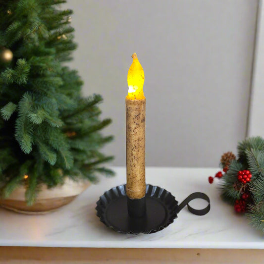 Decorative candle with a Christmas tree and ornaments in the background