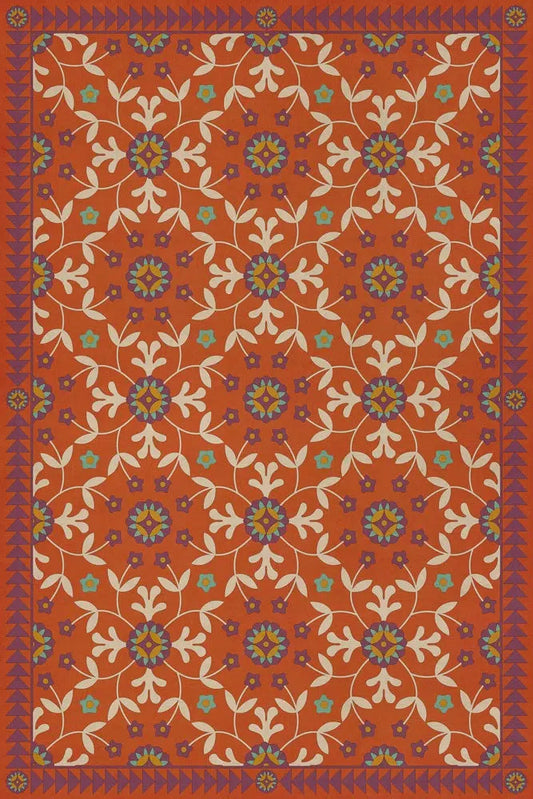 A rectangular floor cloth with a floral pattern in red, orange, and blue hues, featuring a geometric design.