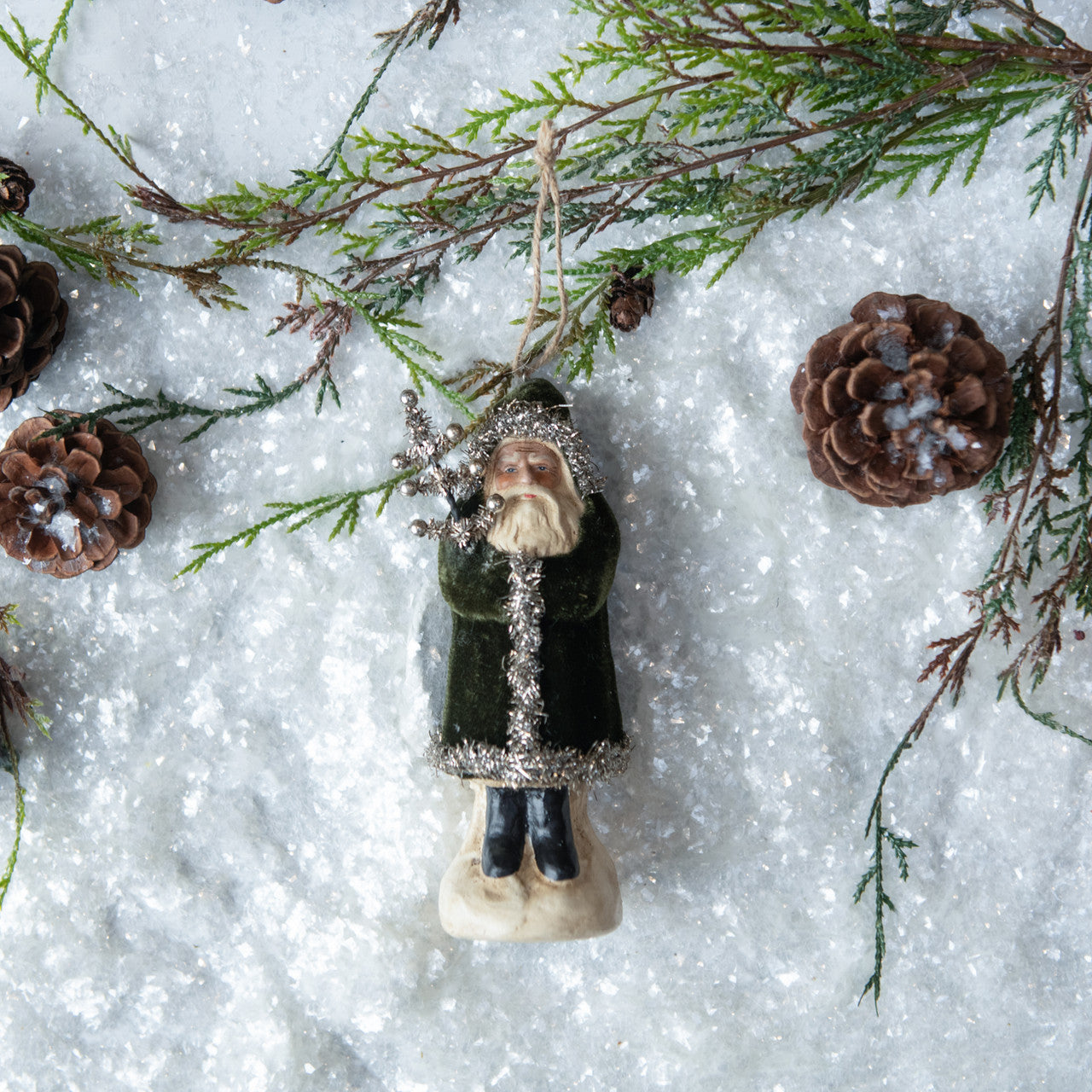 Decorative angel ornament with greenery and pinecones on a snowy background