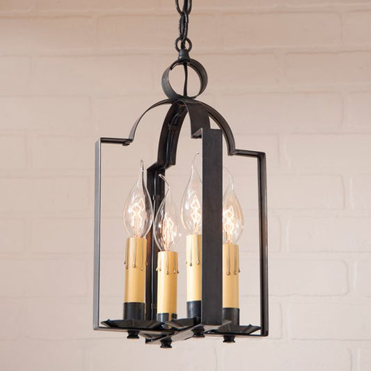 Decorative chandelier with four light bulbs against a white brick wall background