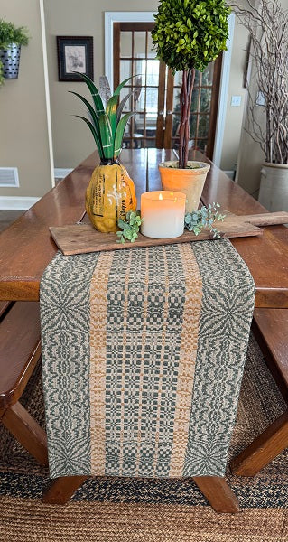 Dining table with a patterned table runner, candle, and decorative items.