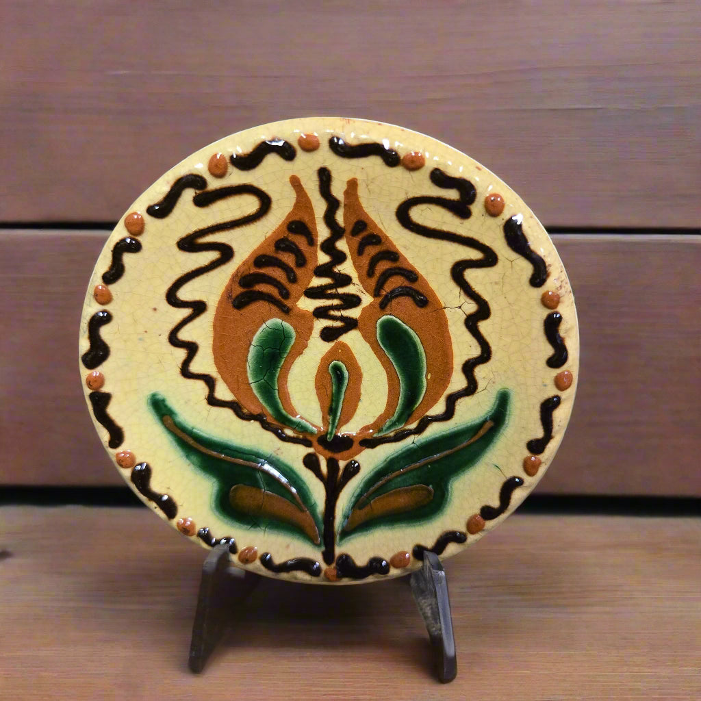 Small round redware plate with a tulip and yellow, brown and green hues