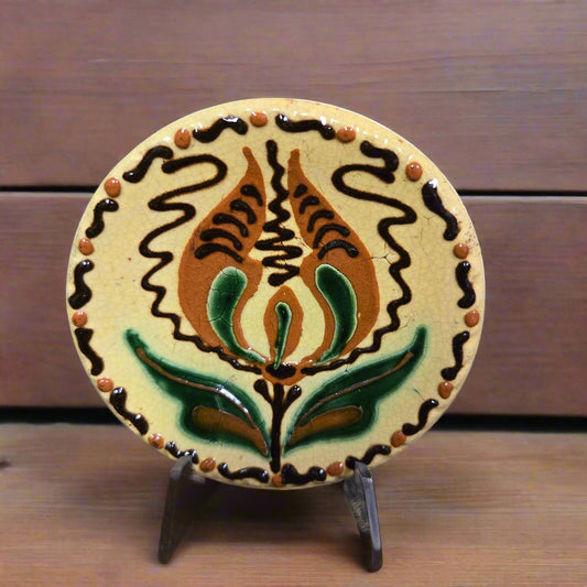 Small round redware plate with a tulip and yellow, brown and green hues