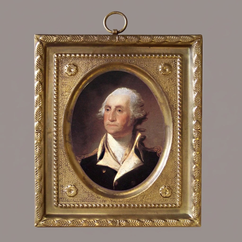 Print of George Washington in an embossed brass frame with ring hook on a white background.