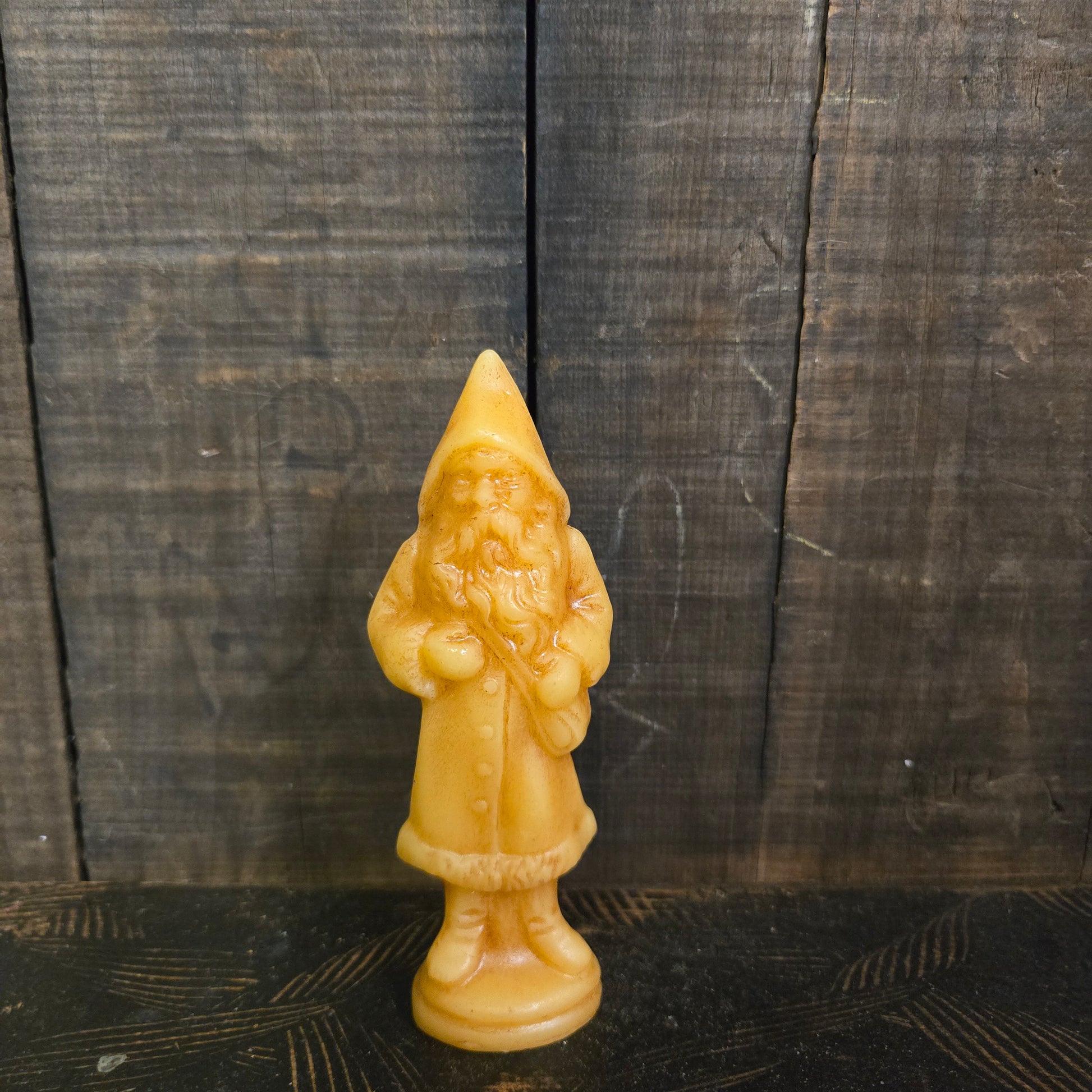 Beeswax figure of a German Santa on a textured wooden surface