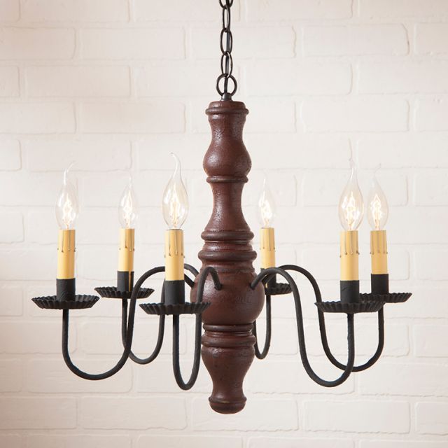 Wooden chandelier with six candle-style lights on a white brick wall background