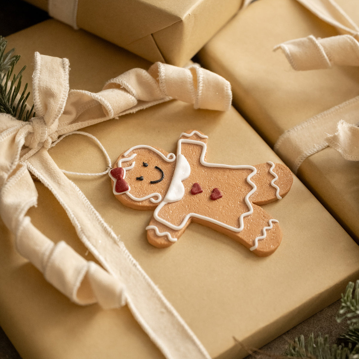 Decorative gingerbread man cookie on a wrapped gift with a beige ribbon.