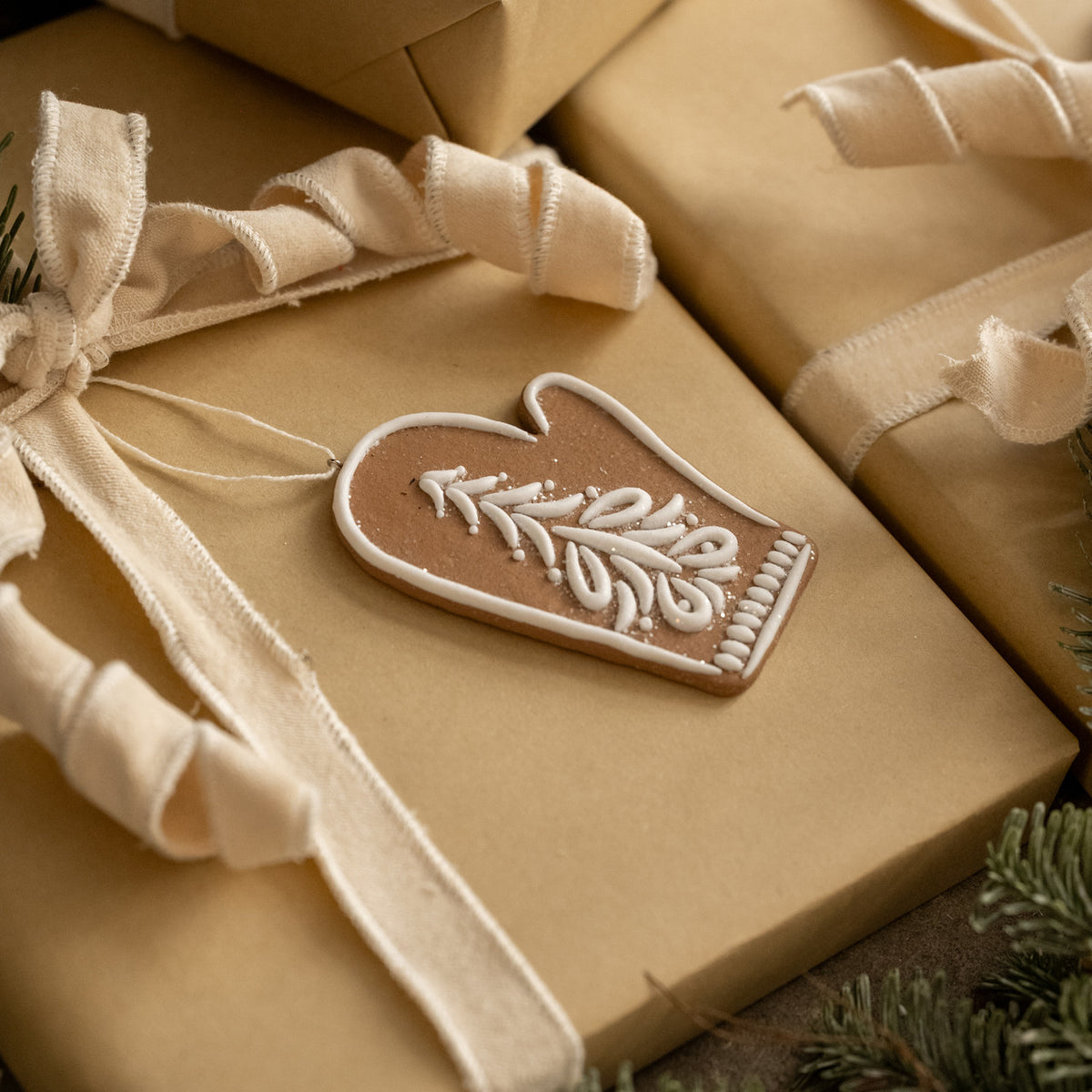 Gift box wrapped in brown paper with a decorative tag and ribbon, surrounded by greenery.