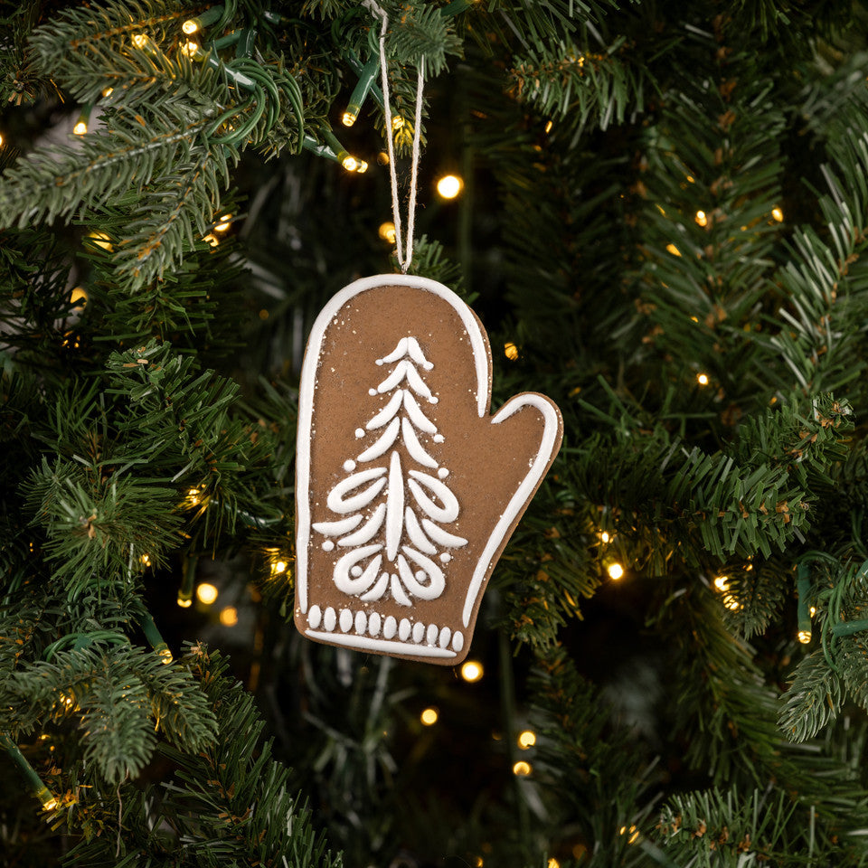 Decorative mitten ornament with a tree design hanging on a Christmas tree.