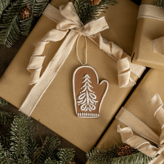 Gift box with a decorative mitten ornament on a Christmas-themed background