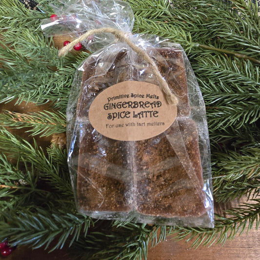 A pack of Gingerbread Spice Latte wax melts placed on a pine branch, with a label that reads 'Gingerbread Spice Latte' for use with essential oils.