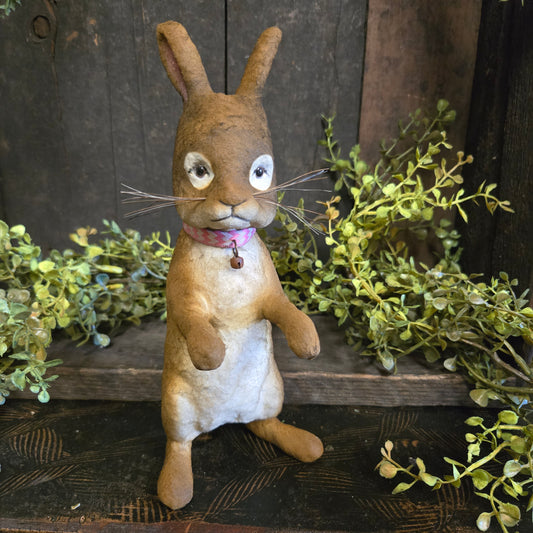 Vintage-style stuffed animal rabbit with greenery on a rustic wooden background