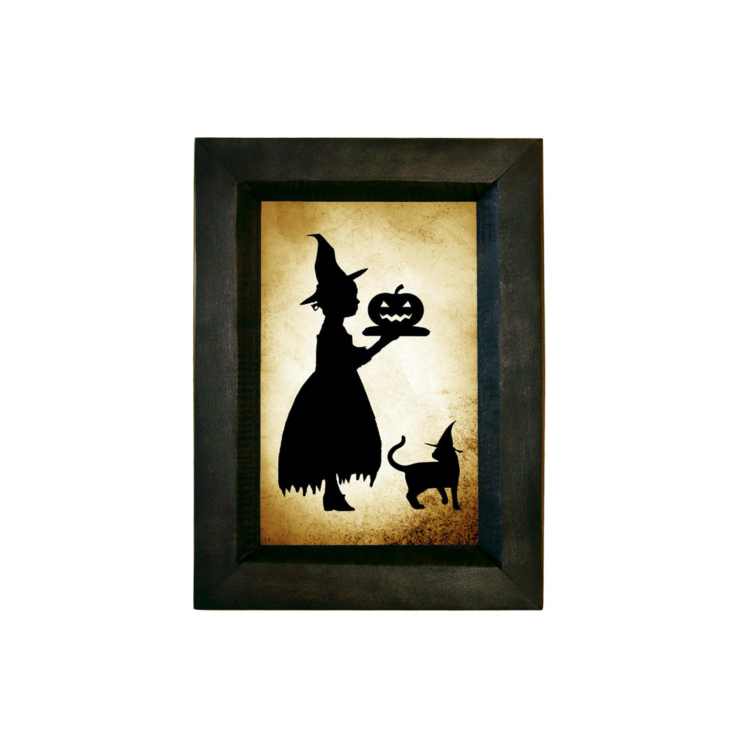 Girl witch serving pumpkin printed paper silhouette in frame on white background