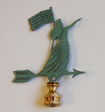 A verdigris lamp finial in the shape of a woman holding a flag, with a gold-colored metal base.