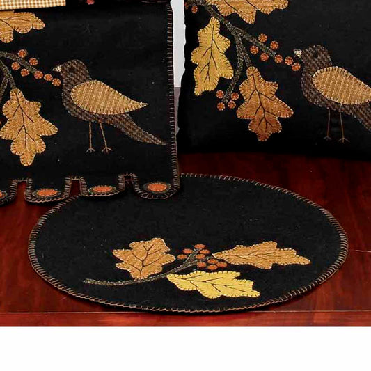 A set of two candle mats with a bird and leaf design, one mat is folded and the other is laid out, both with embroidered details.