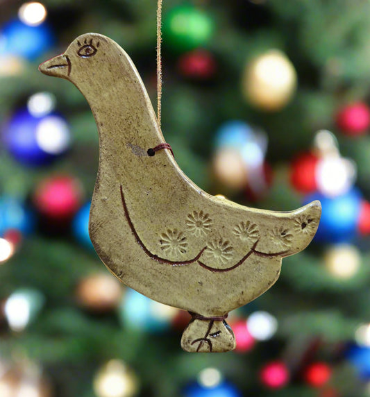 Decorative ceramic dove ornament against a blurred Christmas tree background with colorful lights.