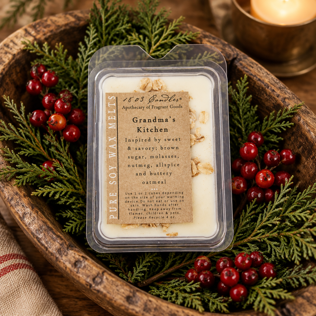 A clear plastic tub of soy wax melts labeled 'Grandma's Kitchen' by 185 Gummies, styled on a rustic wooden tray with evergreen branches and red berries.